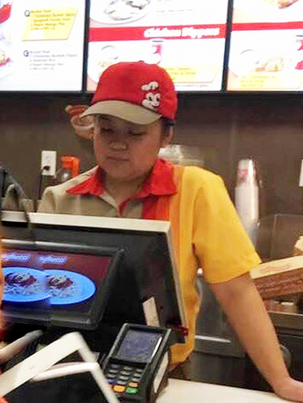 Cashier Francesca Aquino prepares an order for a customer at Jollibee in uniform.