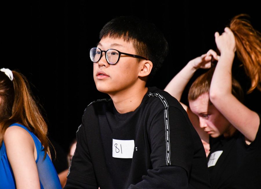 Looking in the distance, Max Song enjoys a brief moment during auditions. His badge shows his number in the auditions.