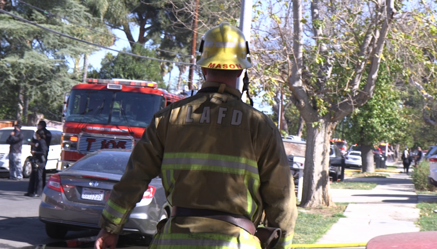 Firefighter walking on sidewalk to confirm that the fire has not spread any further.