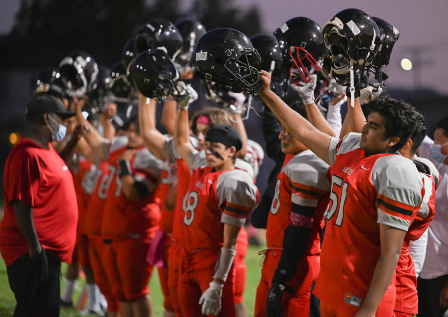 The VNHS wolves raise their helmets in the air during the national anthem to kick off the homecoming game. The Homecoming game on Oct. 2, 2021 ended in a defeat for the home team 35-8 against Panorama. 