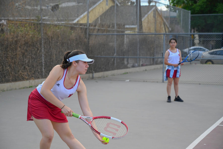 CATS VS. DOGS: Jacqueline Recinos prepares to serve the ball to her opponent on the San Fernando Tigers as Ariel Gutkin, her doubles partner, waits on the side. The Wolves lost their final home game 5-2. 