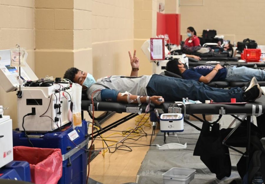 POSITIVE VIBES! While giving blood, a student holds up a peace sign. 