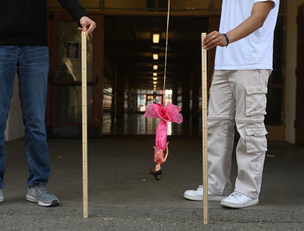 Students measure the distance between the doll and the ground.