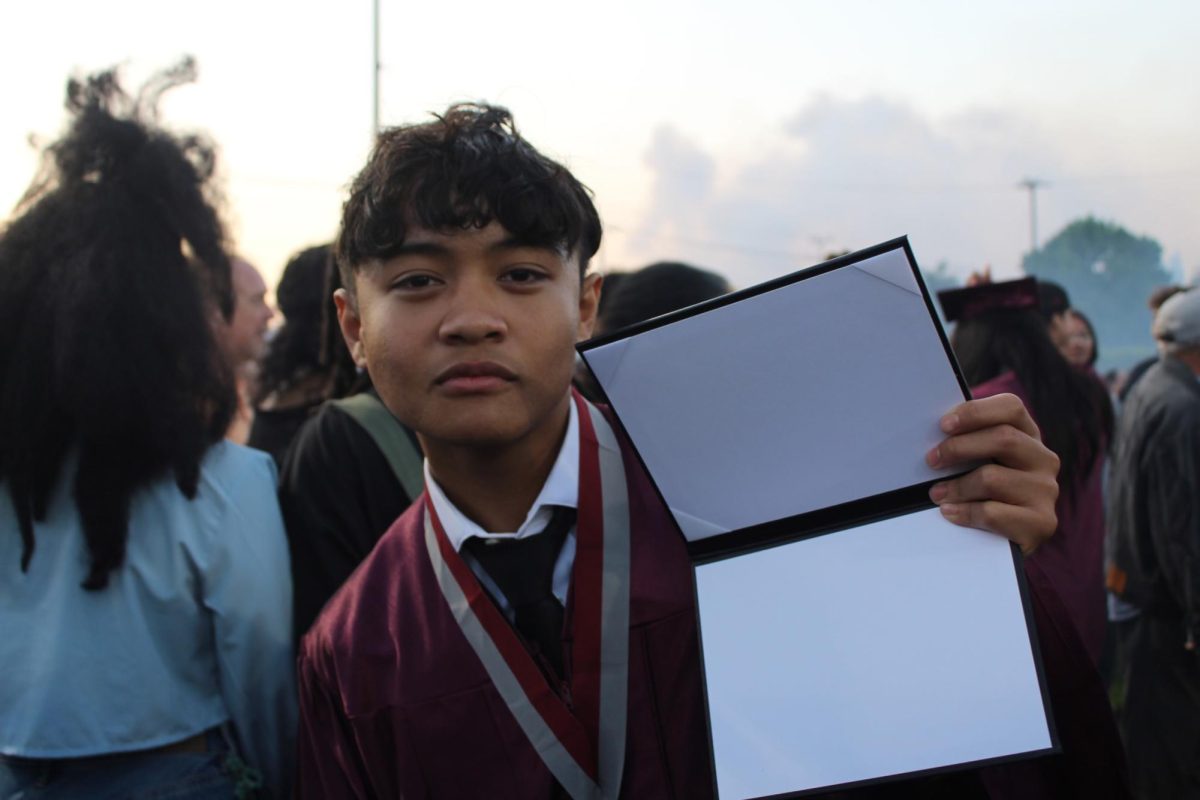 Just after the ceremony, graduate Jalyn Bautista holds up his fake diploma, serving as a place holder until he receives his real one the following day.