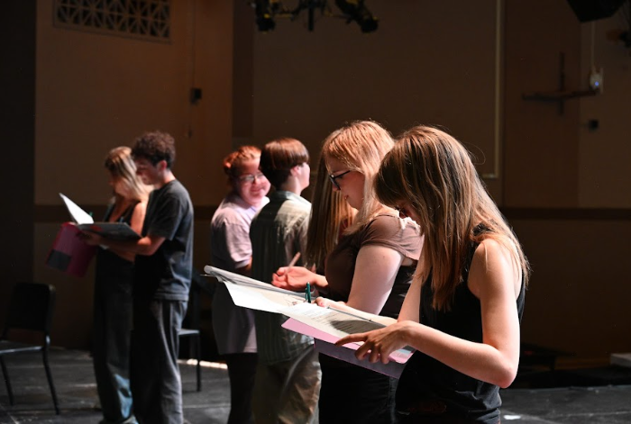 The seven cast members who make up the ensemble glance down at their scripts before running the opening sequence for the first time.