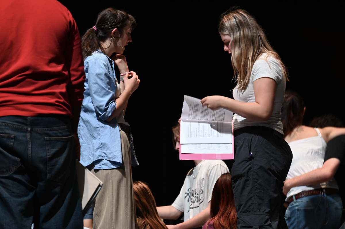 (From L to R) Senior Adrianna Bean and sophomore Amelia Probst ruffle through their scripts, comparing blocking, before starting.