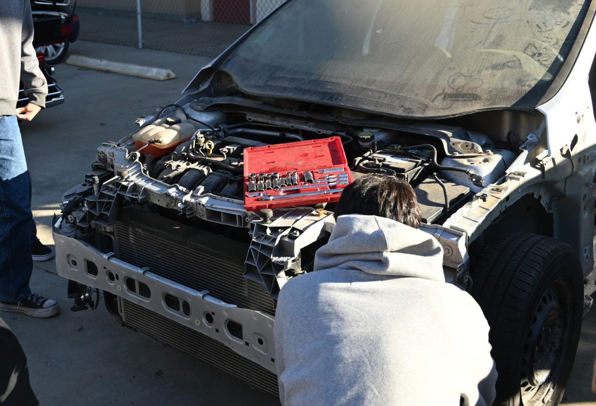 Autoshop student demonstrating how to attach a headlight to his peers.