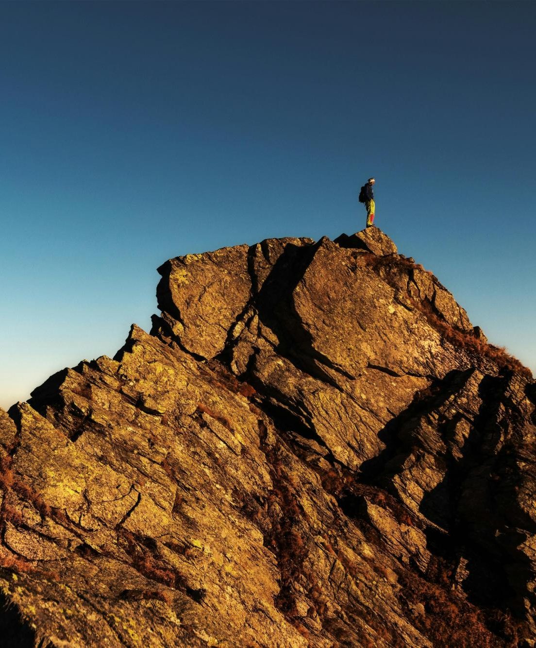 A man standing on top of a rock meant to illustrate the difficulty of reaching some goals.