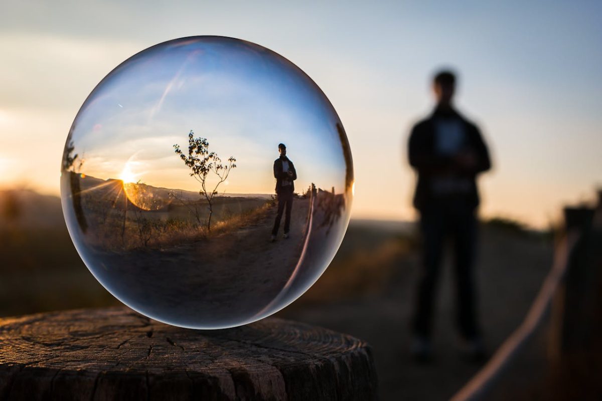 A man's distorted image seen through a glass ball.