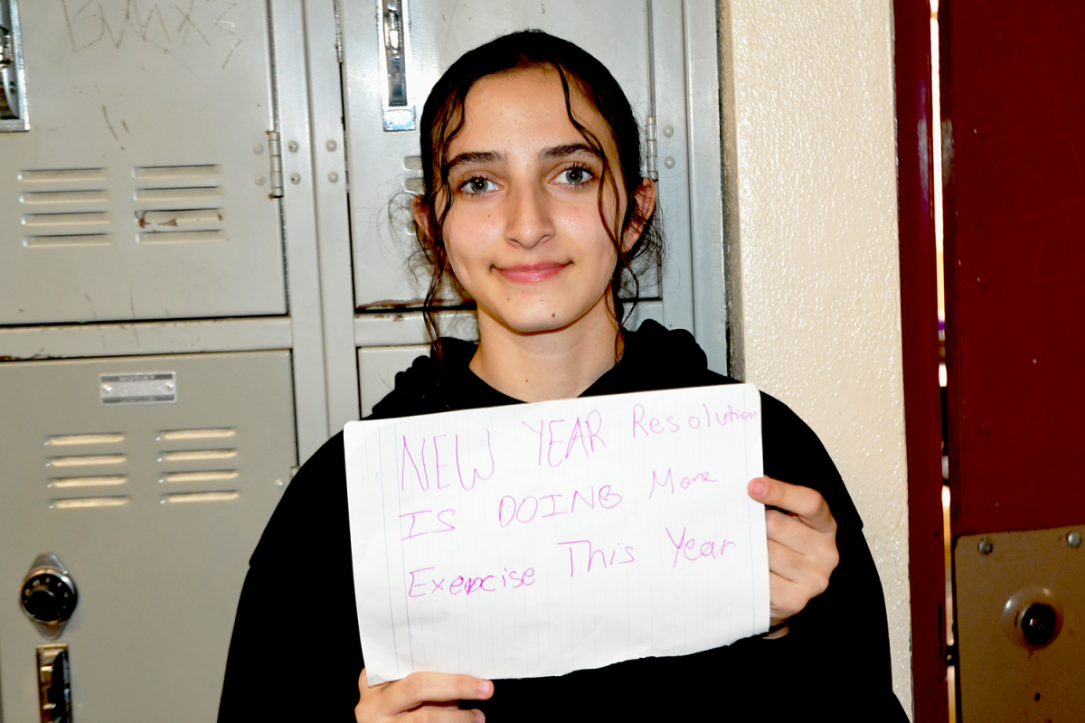 Sophomore Emily Isajan holds up a piece of paper with her New Year’s resolution of exercising more. 