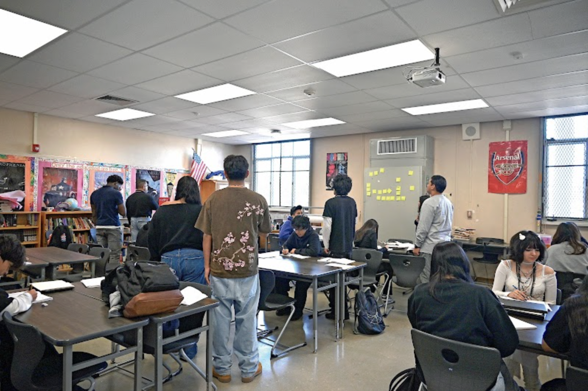 ALL RISE As members of the student body recite the Pledge of Allegiance on the PA, some students stand, placing their right hands over their hearts, while other remain seated.